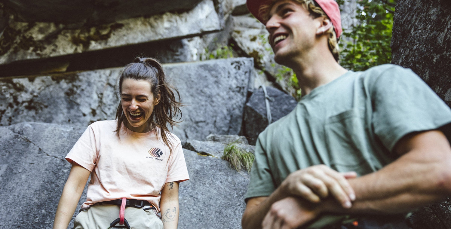 Two climbers taking a break on a rocky path with climbing gear.